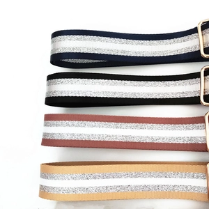 Detail of adjustable woven bag straps with silver stripes and golden metal buckles