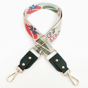 Detail of colorful jacquard flower guitar strap with green leather and gold hardware