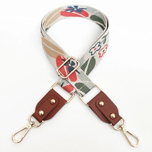 Macro detail of colorful floral jacquard pattern bag strap with gold metal hooks