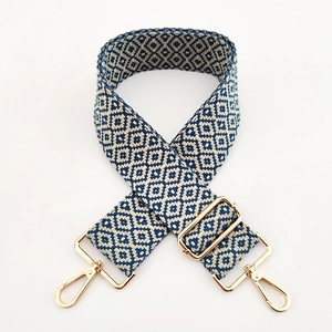 Detail of adjustable woven shoulder strap with blue geometric pattern and gold hardware
