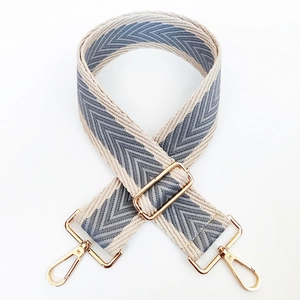 Detail of adjustable woven shoulder strap with grey chevron pattern and gold metal hooks