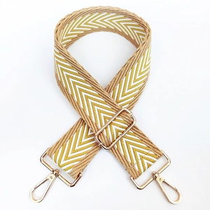 Detail of yellow and white V-patterned wide shoulder strap with gold metal lobster clasps