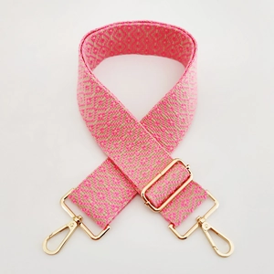 Detail of adjustable woven shoulder strap with pink geometric patterns and gold metal clasps