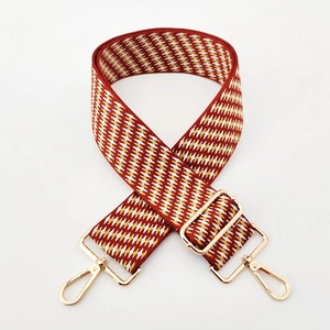 Close-up of a 5cm wide red and yellow geometric jacquard strap with gold metal hardware