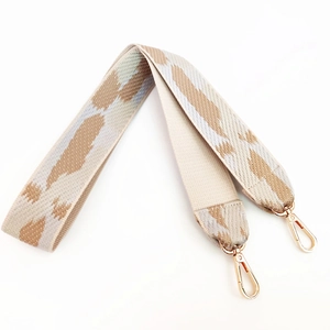 Close-up of woven bag strap with leopard pattern and gold-tone metal lobster clasps