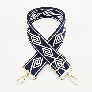 Detail of adjustable wide woven strap with navy diamond pattern and gold metal hooks