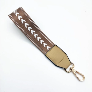 Macro detail of brown fishbone woven wrist strap with leather wrap and gold lobster clasp