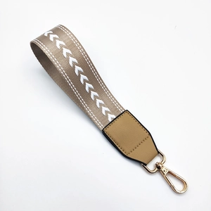 Close-up of khaki woven strap with white V-pattern and golden lobster clasps for bags
