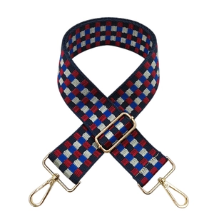 Detail of red and blue checkered woven bag strap with adjustable gold metal buckle