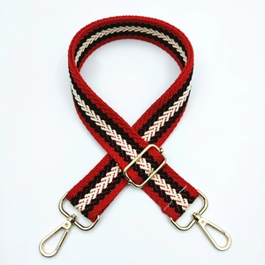 Close-up of adjustable woven bag strap with red geometric pattern and gold hardware