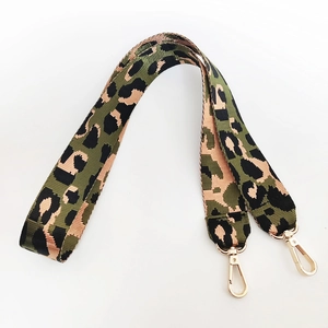 Detail eines breiten Schultergurts mit Camouflage-Leopardenmuster und goldenen Karabinerhaken