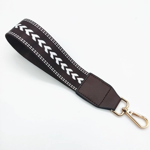 Close-up of woven dark brown wrist strap with heart pattern and gold swivel clasp