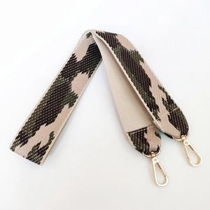 Close-up of wide camouflage woven canvas bag strap with golden metal lobster clasps