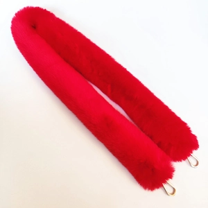 Detail of red faux fur handbag strap with polished gold lobster clasps on white background