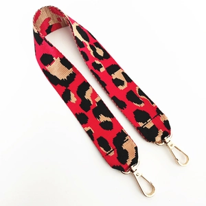 Detail eines roten Taschenriemens mit Leopardenmuster und goldenen Karabinern
