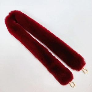 Macro shot of fluffy wine red faux fur handbag strap with gold metal lobster clasps