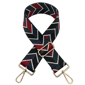Close-up of jacquard woven geometric bag strap with golden metal lobster clasps