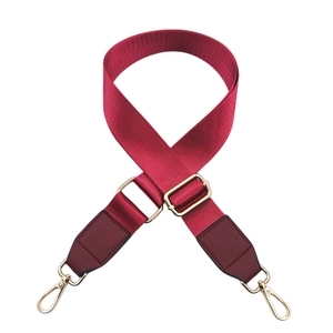 Close-up of adjustable burgundy nylon bag strap with leather ends and gold metal hooks