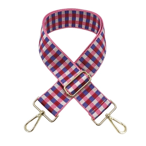Detail of colorful checkered guitar-style wide woven bag strap with golden metal buckles