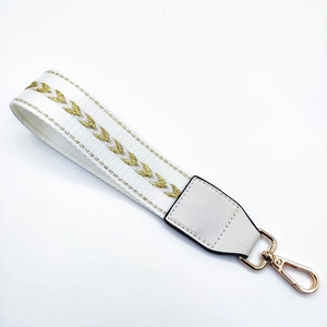 Detail of white woven bag strap with golden arrow embroidery and swivel lobster clasp