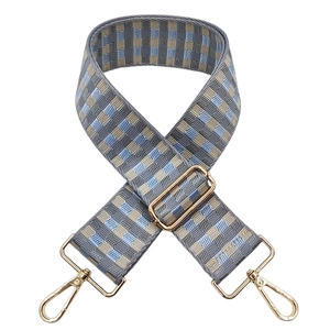 Close-up of blue and brown checkered wide bag strap with gold metal lobster clasps