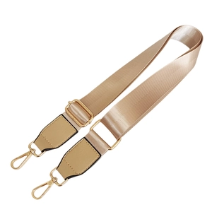 Detail of champagne gold nylon shoulder strap with metallic swivel hooks and leather trim