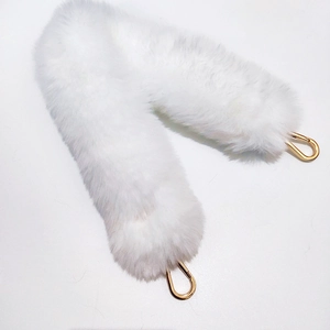 Detail of fluffy white faux fur bag strap with polished gold metal lobster clasps