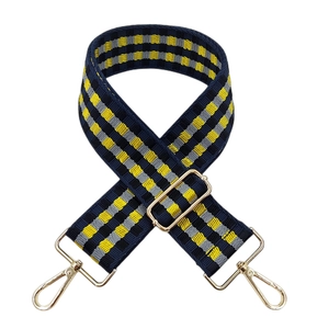 Detail of adjustable checkered navy and yellow woven bag strap with gold metal lobster clasps