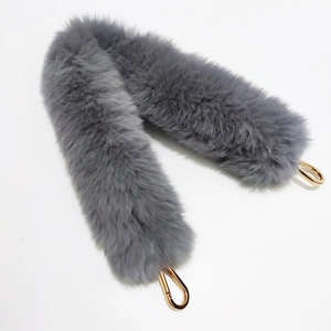 Detail of soft grey faux fur handbag strap featuring shiny gold metal lobster clasps