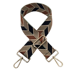Detail of adjustable woven bag strap with retro geometric wave pattern and gold metal hooks