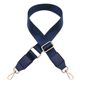 Detail of navy nylon bag strap with gold metal hardware and leather reinforcement