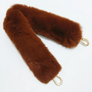 Detailed view of plush brown faux fur bag strap with gold metal carabiner clips