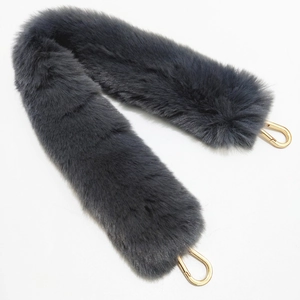Detail view of dark grey faux fur bag strap with golden lobster claws on white background