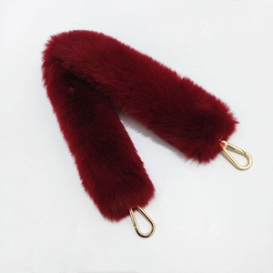 Close-up of fluffy burgundy faux fur bag strap with golden metal lobster clasps