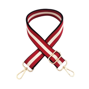 Détail de la bandoulière ajustable en toile à rayures rouges, blanches, noires et dorées