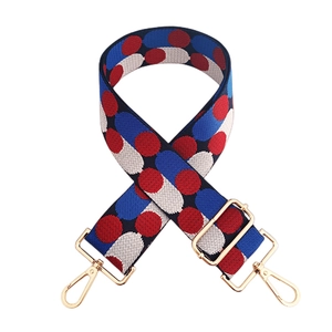 Detailed view of adjustable jacquard bag strap with red and blue polka dots and gold clasps