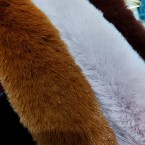 Macro shot of fluffy faux fur handbag straps in brown, pink and dark red striped patterns