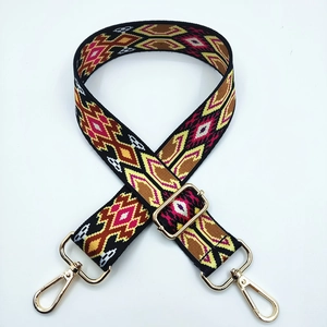 Close-up of ethnic geometric pattern woven strap with golden metal lobster clasps and buckles