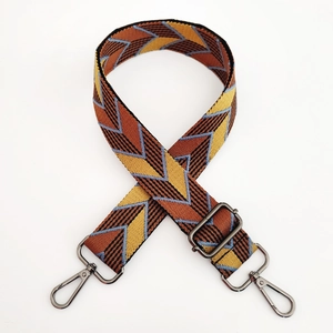 Macro view of woven wide shoulder strap with colorful geometric jacquard and metal buckle