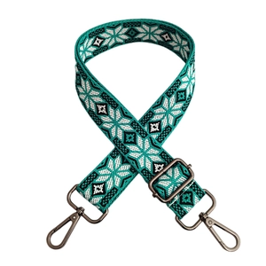 Detail of bohemian jacquard bag strap with teal snowflake patterns and gunmetal hardware