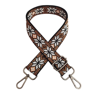 Close-up of ethnic embroidered bag strap with geometric snowflake pattern and metal buckles