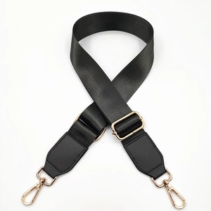 Close-up of adjustable black nylon bag strap with golden metal hooks and leather reinforcement