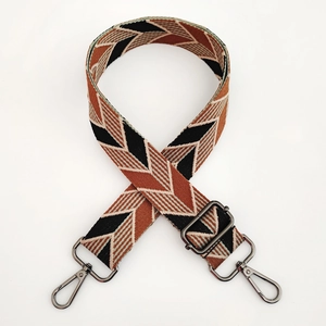 Close-up of geometric jacquard shoulder strap with dark metal hooks and buckles