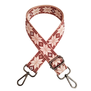 Macro detail of red and white ethnic geometric pattern woven bag strap with swivel hooks