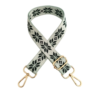 Detail of teal woven shoulder strap with green snowflake pattern and gold lobster clasp