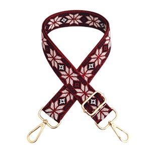 Close-up of burgundy ethnic style woven handbag strap with golden metal carabiner hooks