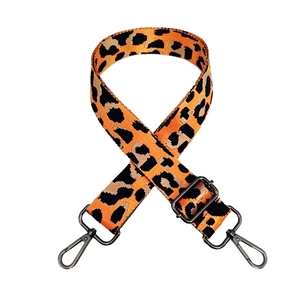 Detail of adjustable leopard print bag strap with orange webbing and black metal hooks