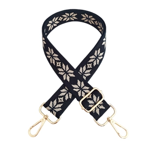 Close-up of ethnic style embroidered bag strap with golden metal swivel hooks and length buckle