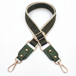 Detail of adjustable dark green woven bag strap with golden metal hooks and hardware