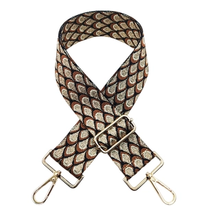 Close-up of adjustable woven shoulder strap with jacquard peacock pattern and gold hardware